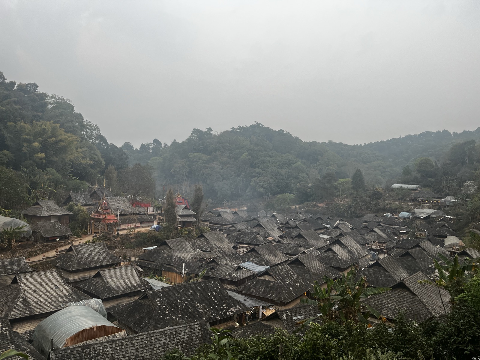 Dusk in a Dai village on Jingmai Mountain, kitchen smoke curling into the evening